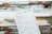 A rustic menu with the header 'Tsitrus Café Menu,' featuring various food and drink options such as pizzas, savory pancakes, pot pies, cheesecakes, pancakes, ice cream, cold drinks, and hot drinks. The menu is placed at an angle on a distressed wooden surface with peeling paint in shades of white, teal, and brown.