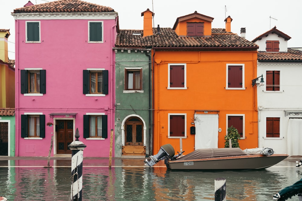 man riding on boat on river near pink concrete building during daytime