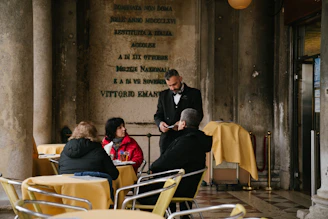 A waiter using a mobile POS device to take orders at an outdoor restaurant patio.