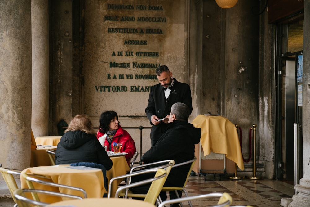 man in black suit sitting on white chair