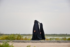 person in black robe walking on brown field during daytime