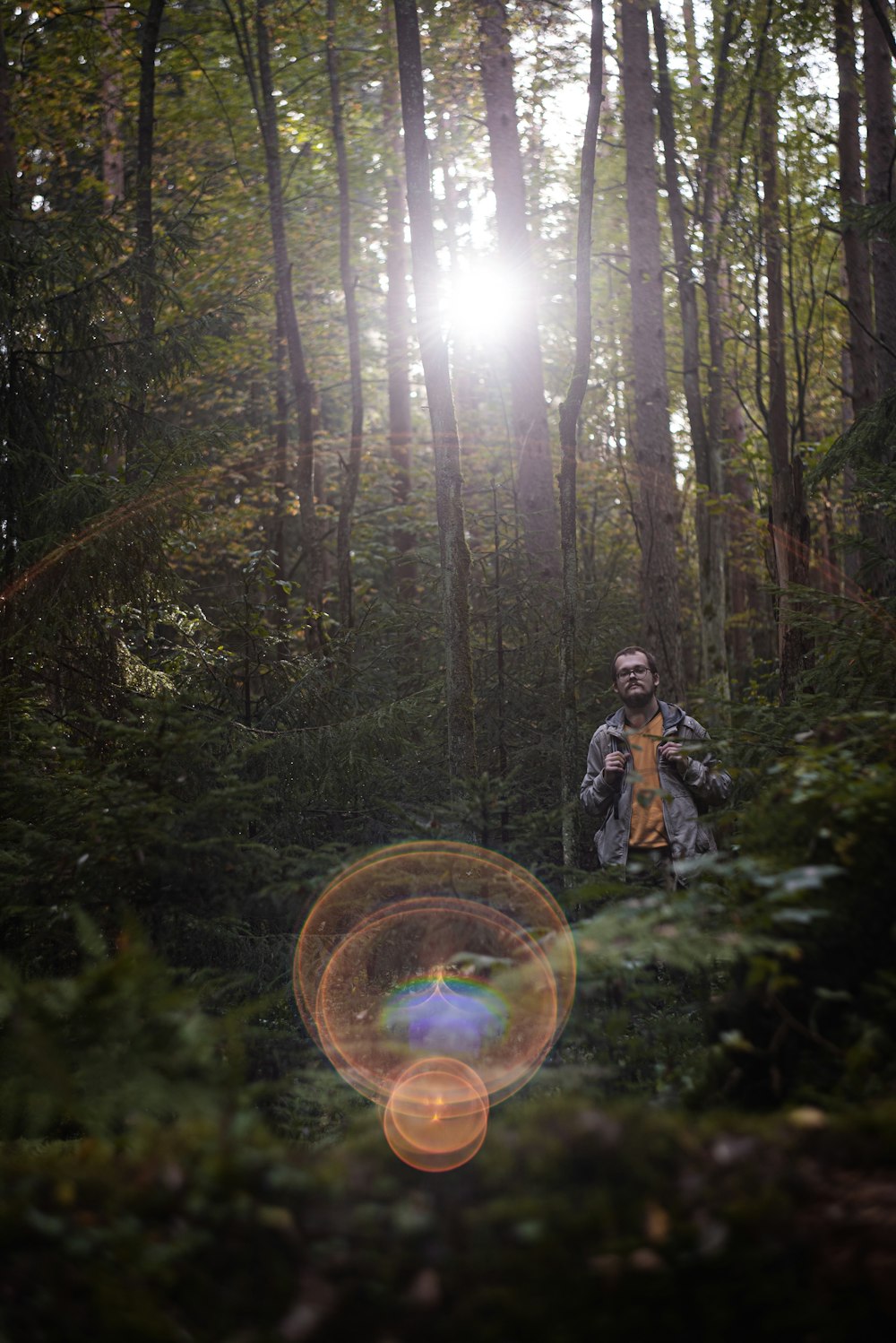 man in black and white jacket holding a bicycle in the woods