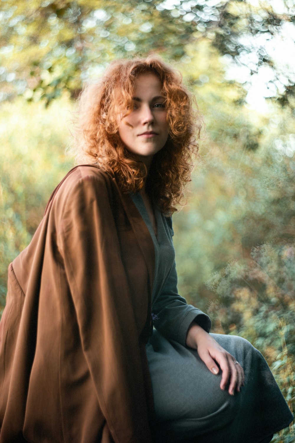 woman in black long sleeve shirt and brown scarf sitting on gray rock