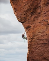 man in black shorts climbing brown rock formation during daytime