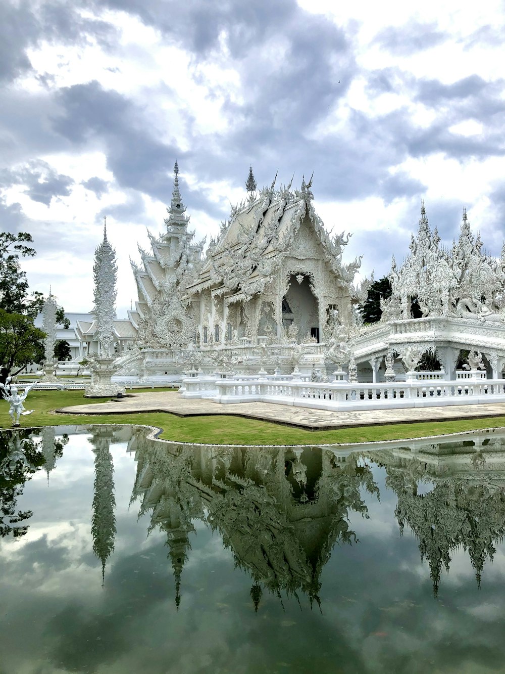 white concrete building near green trees under white clouds during daytime