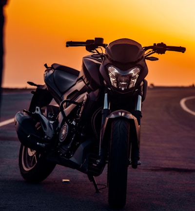 black motorcycle on gray asphalt road during sunset