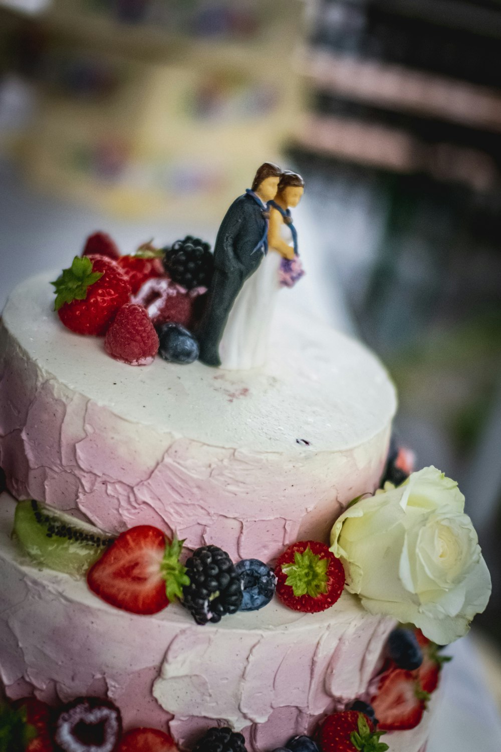 white and pink cake with raspberry and blueberry on top