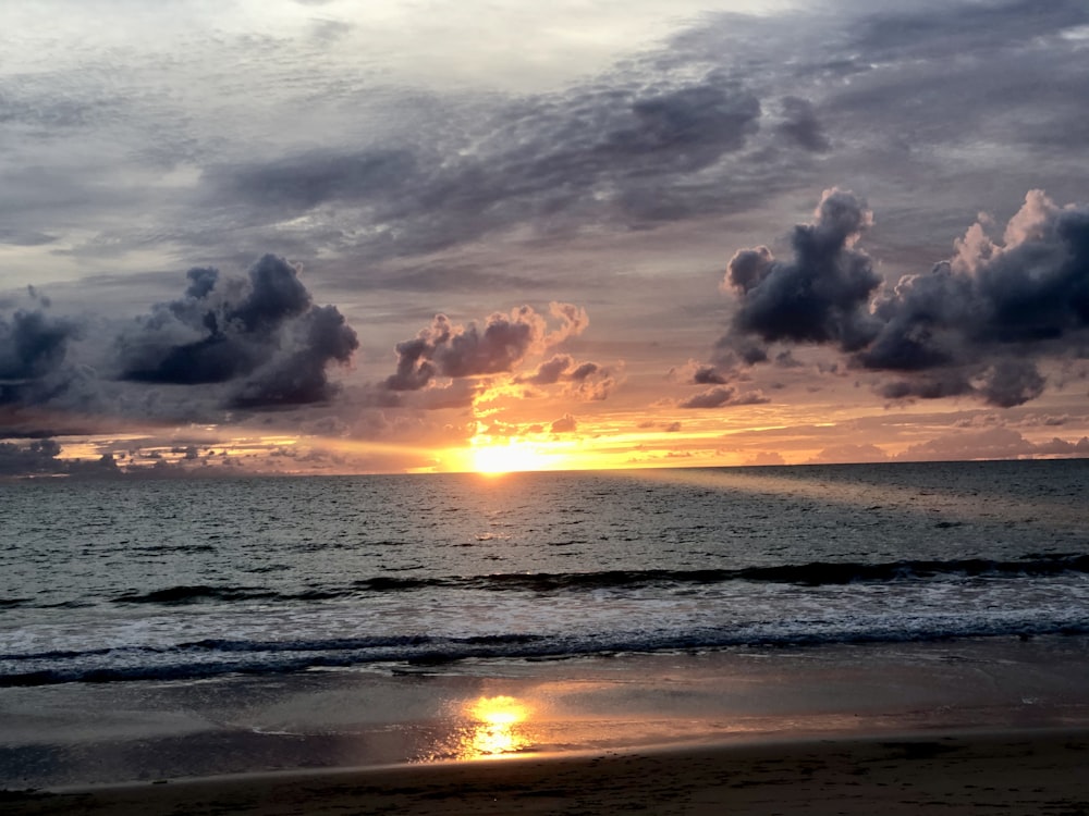 sea waves crashing on shore during sunset