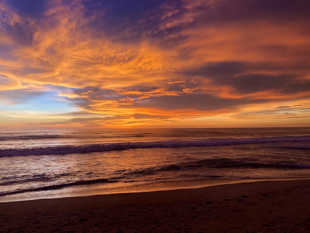 ocean waves crashing on shore during sunset