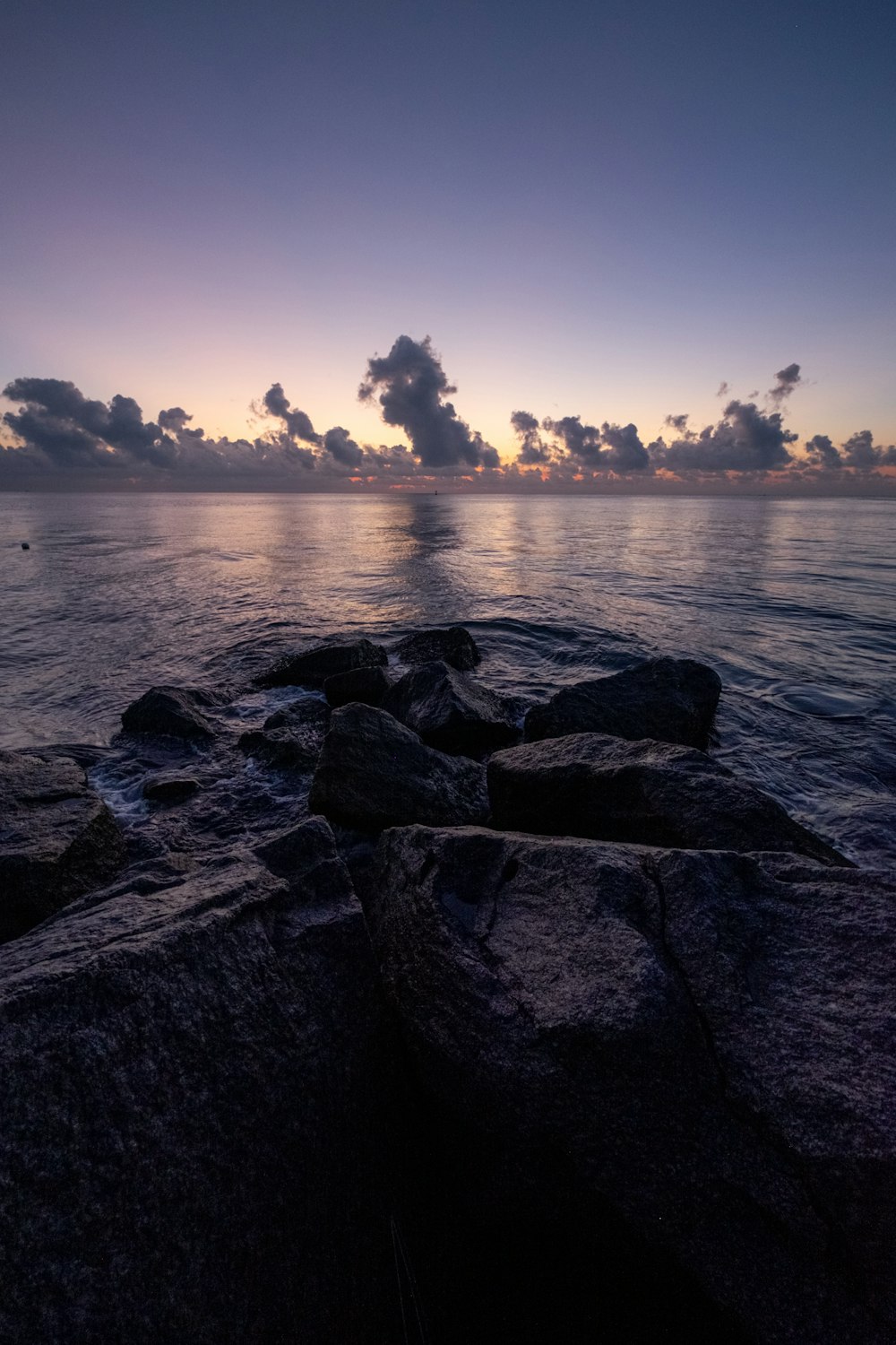 gray rocks near body of water during sunset