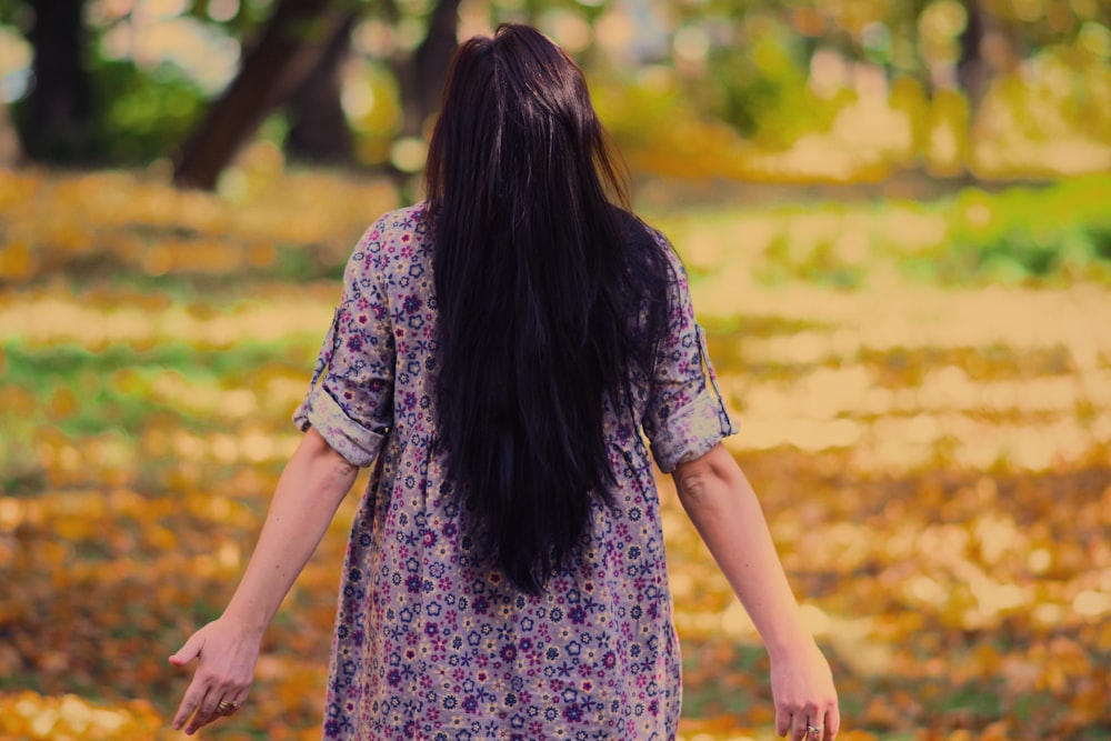 woman in black and pink floral dress standing on brown wooden pathway during daytime