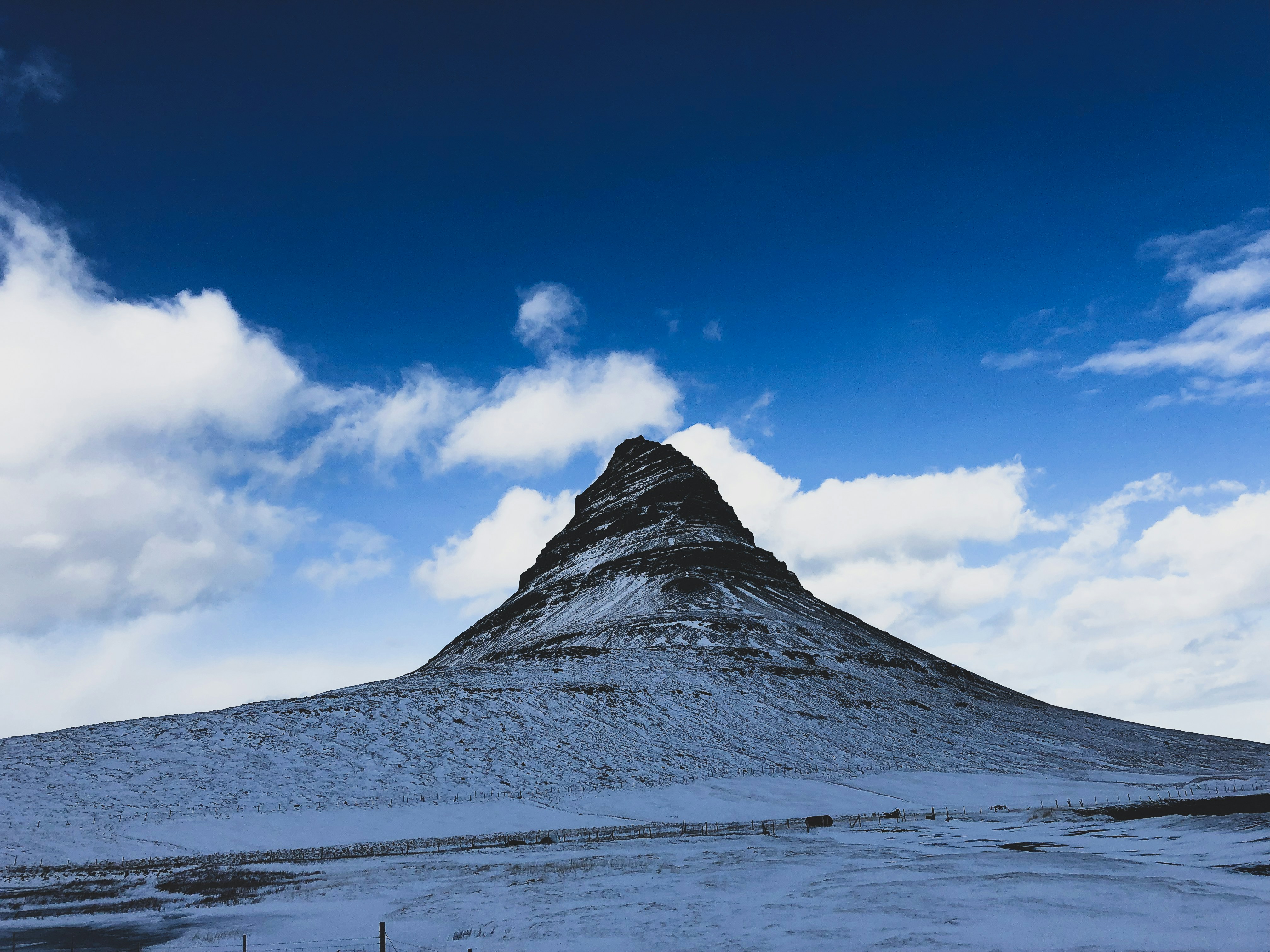a snow covered mountain under a cloudy blue sky
