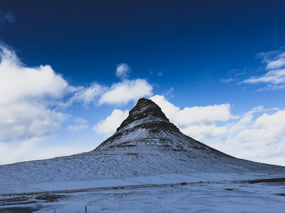 a snow covered mountain under a cloudy blue sky