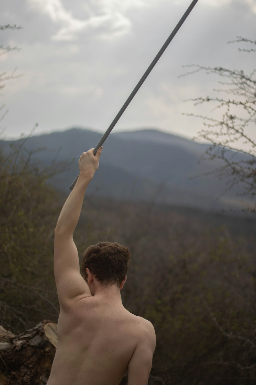 topless man holding stick during daytime