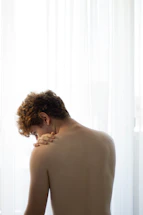 A physiotherapist gently assisting a patient with shoulder exercises in a bright treatment room.