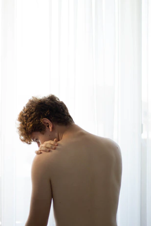 A physiotherapist gently assisting a patient with shoulder exercises in a bright, modern clinic room.