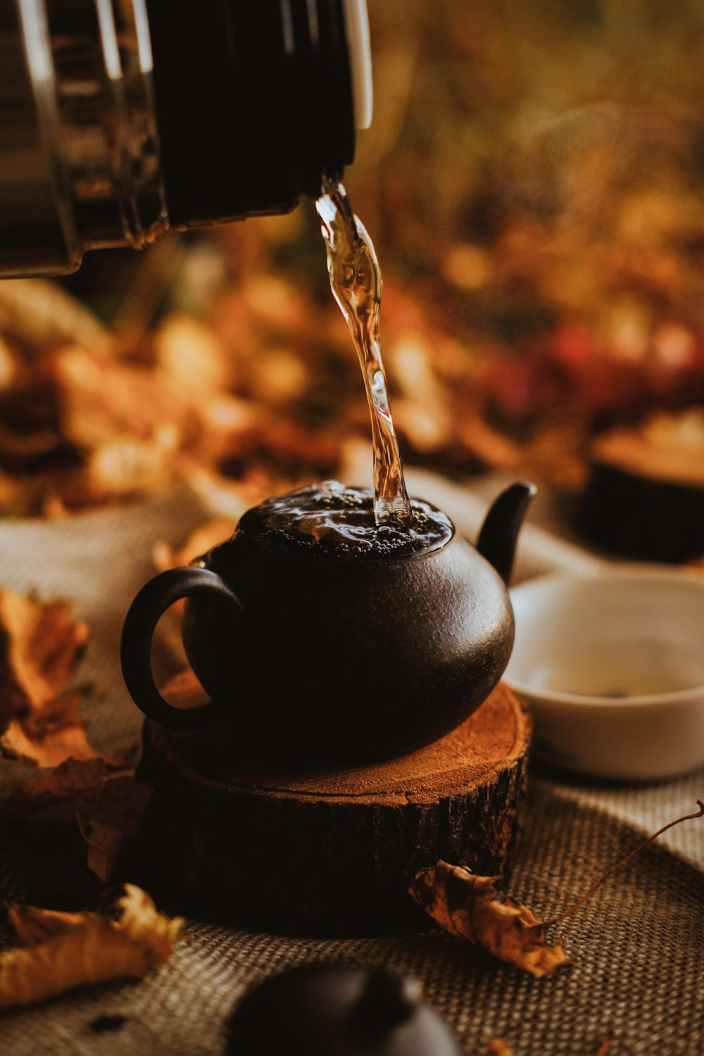 tetera de cerámica negra vertiendo agua en taza de té de cerámica blanca