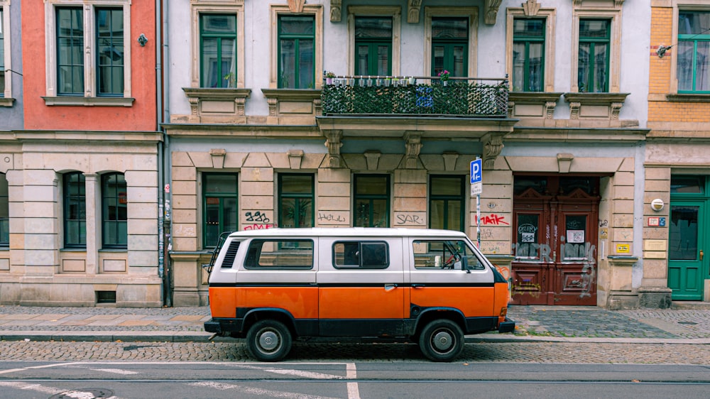 orange and white van parked beside green and white concrete building during daytime