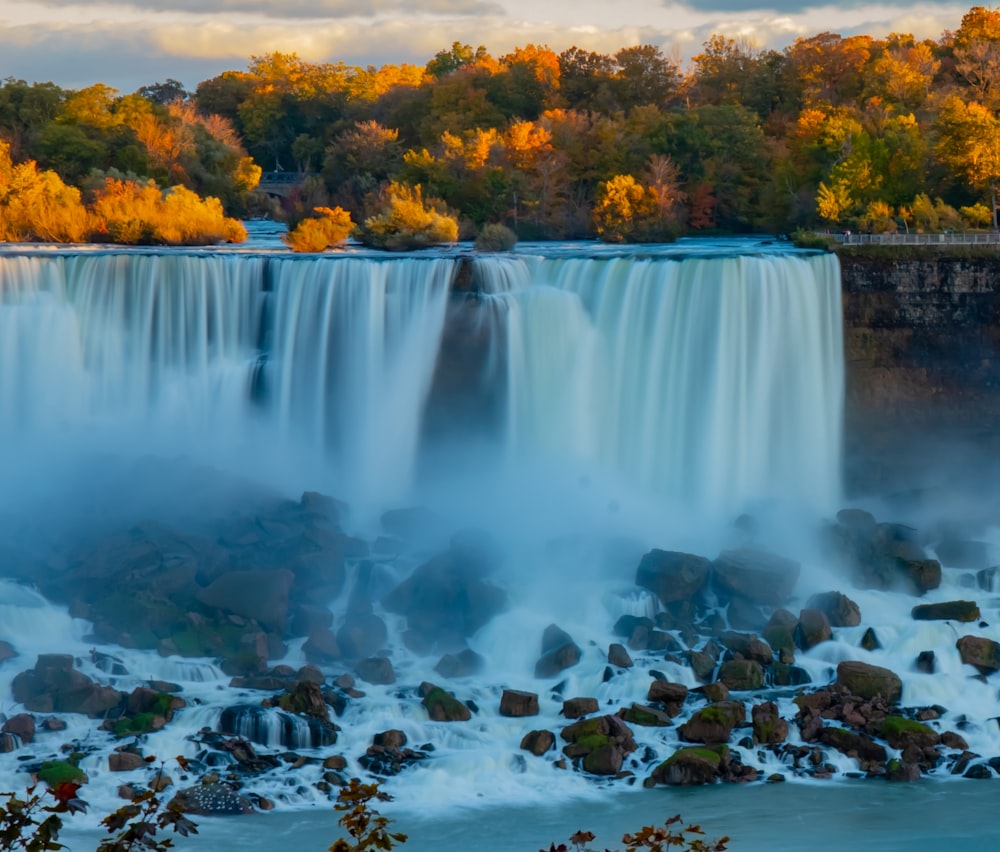 water falls surrounded by green trees during daytime