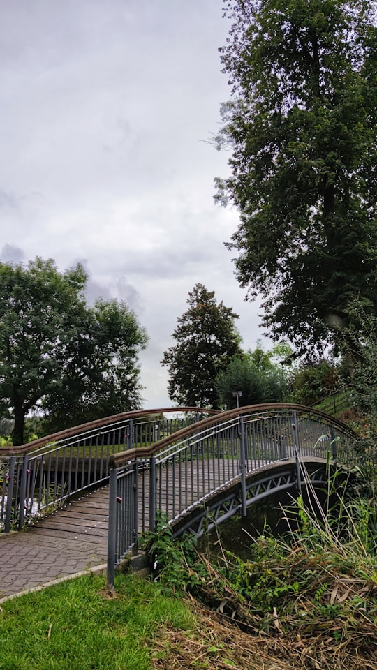brown wooden bridge near green trees under white clouds during daytime in Neustadt am Rübenberge Germany