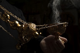 Elegant golden incense holder with smoke swirling against deep black backdrop