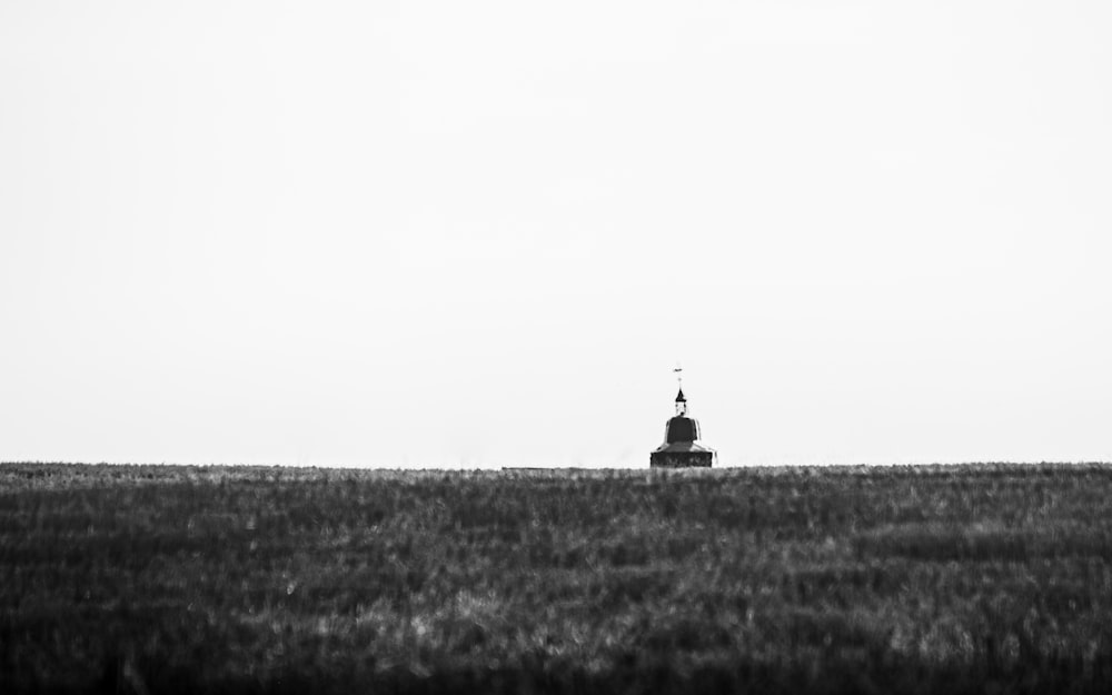 grayscale photo of a black tower in the middle of a field