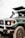 A green Toyota Land Cruiser with a visible front bumper and license plate is parked in an outdoor setting. The vehicle has a raised hood, and one person is partially visible inside the driver’s seat.