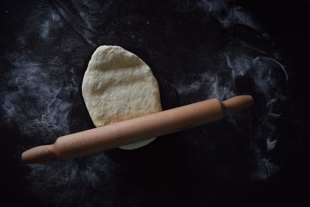 brown wooden rolling pin on black textile