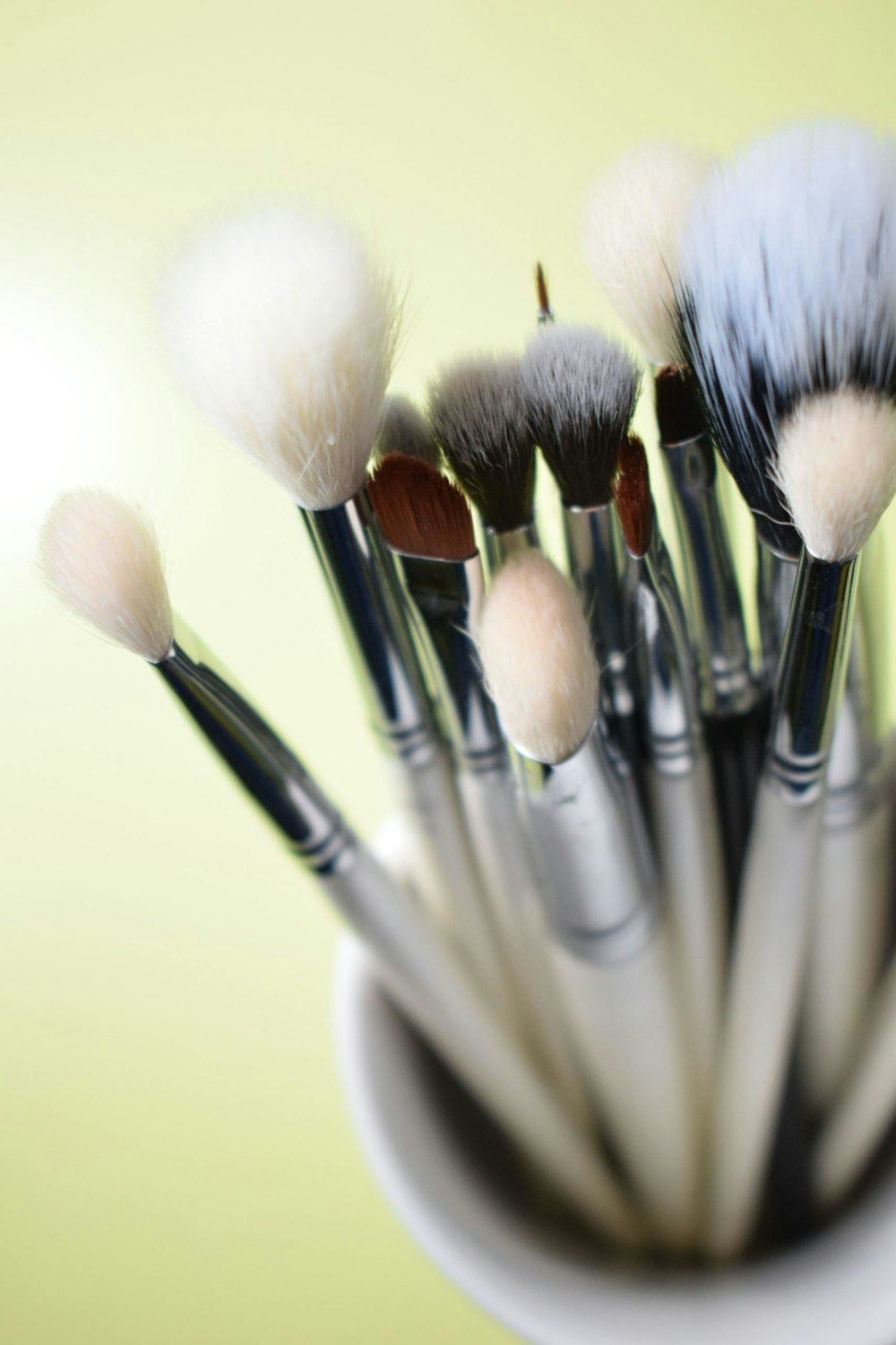 a cup filled with lots of white and black brushes