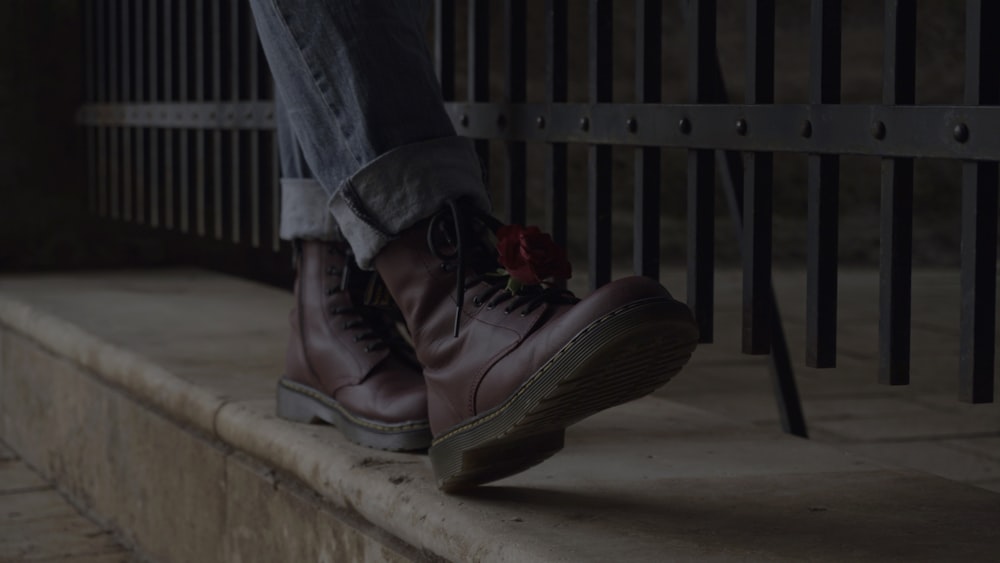 person wearing black leather boots sitting on concrete bench