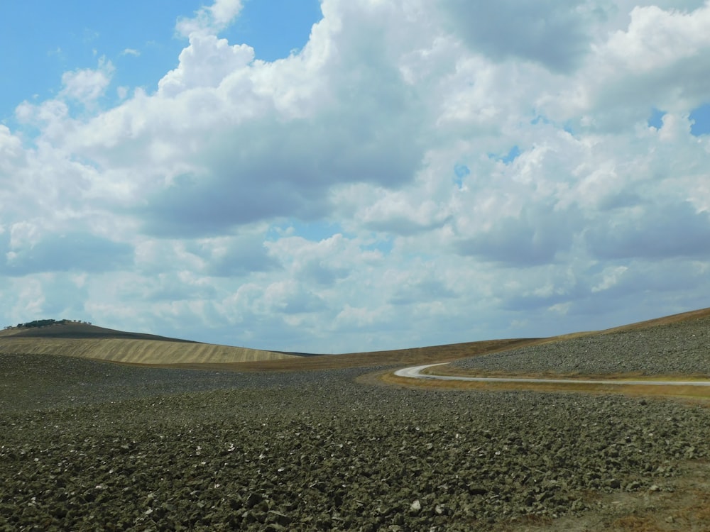 gray asphalt road under white clouds and blue sky during daytime