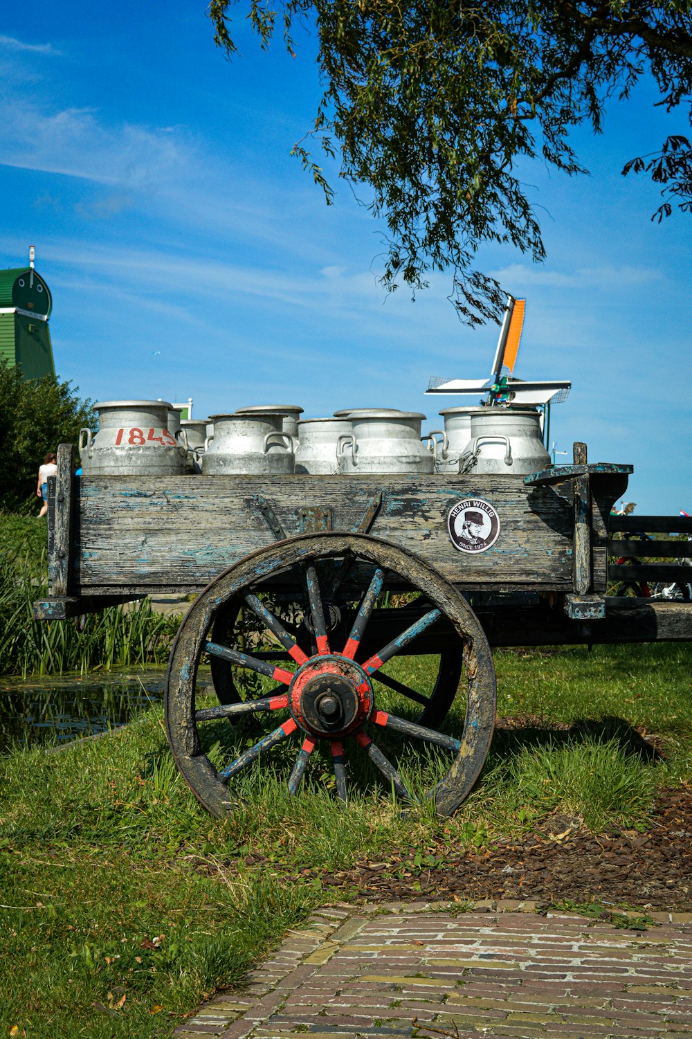 red and black wooden cart on green grass field under blue sky during daytime