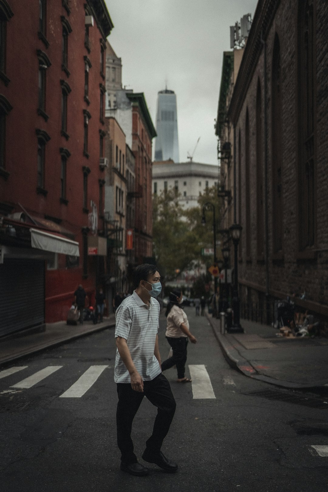 man in white t-shirt and black pants walking on street during daytime