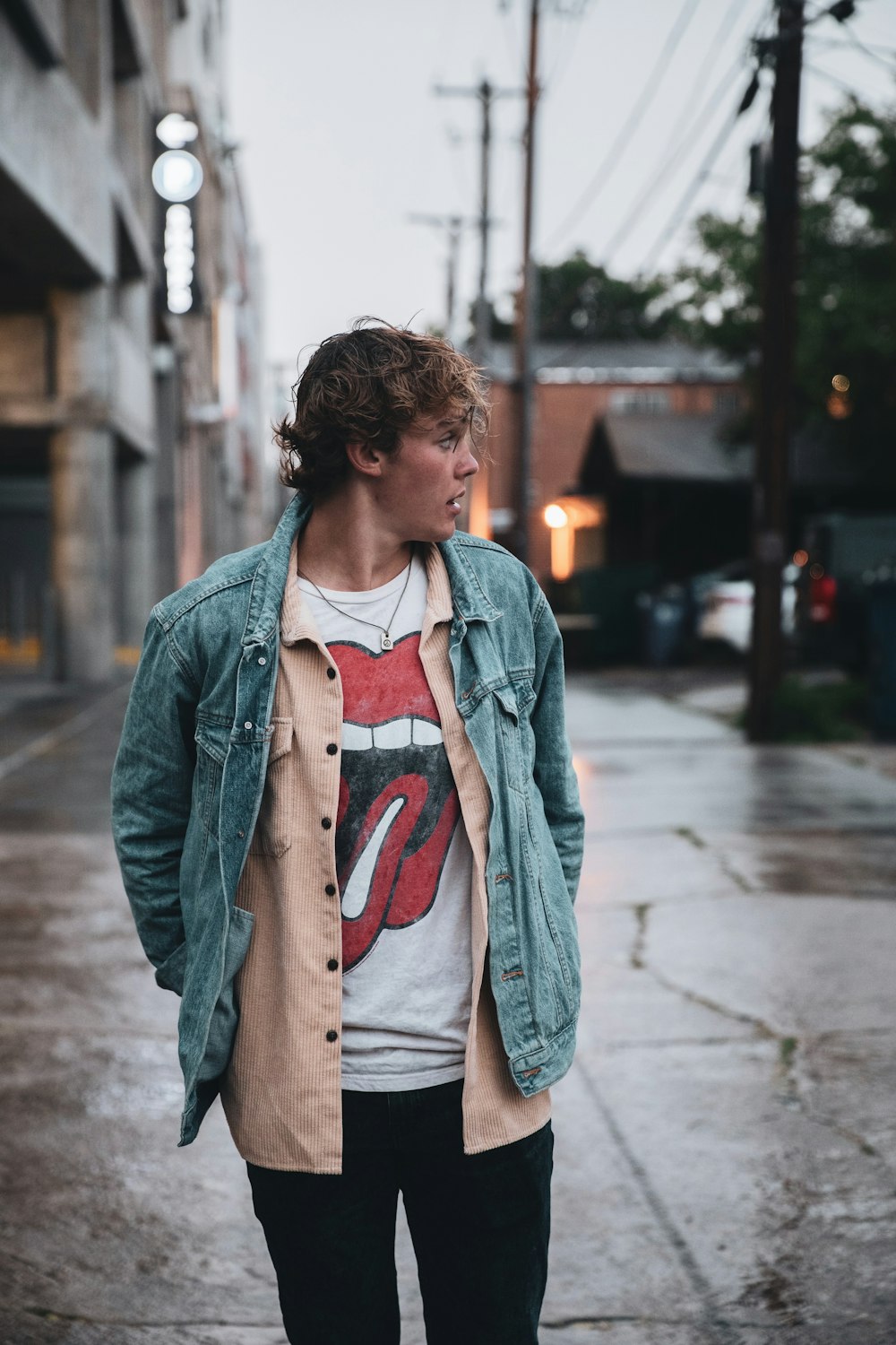 a young man standing on a wet sidewalk