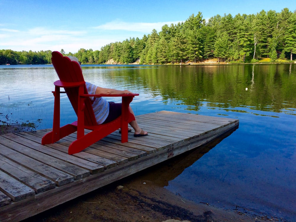 red wooden armchair on dock near lake during daytime