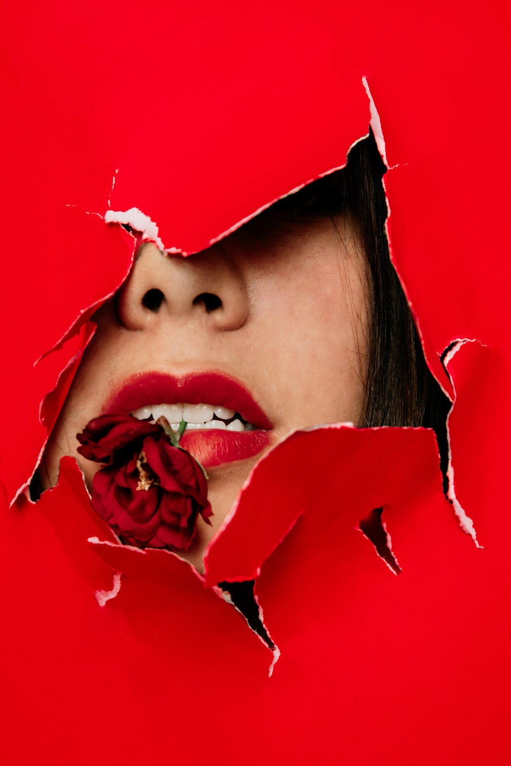Frau mit roten Rosenblättern im Gesicht