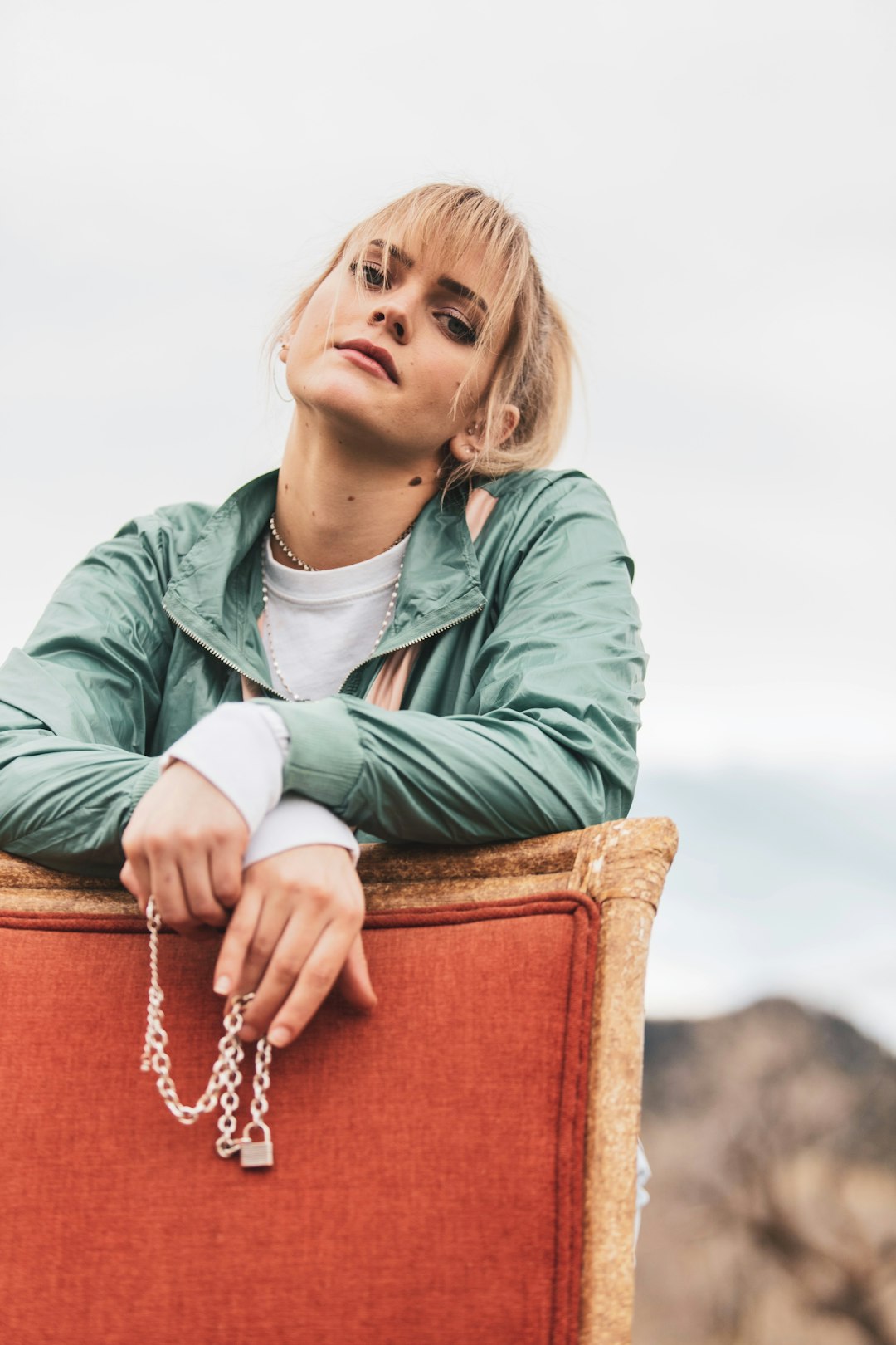 woman in green jacket sitting on brown wooden bench during daytime