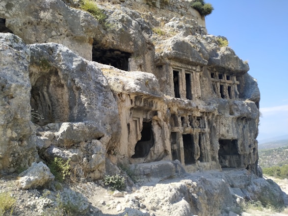 Ancient Egyptian tomb entrance carved into rocky cliffs at sunset in Asasif.