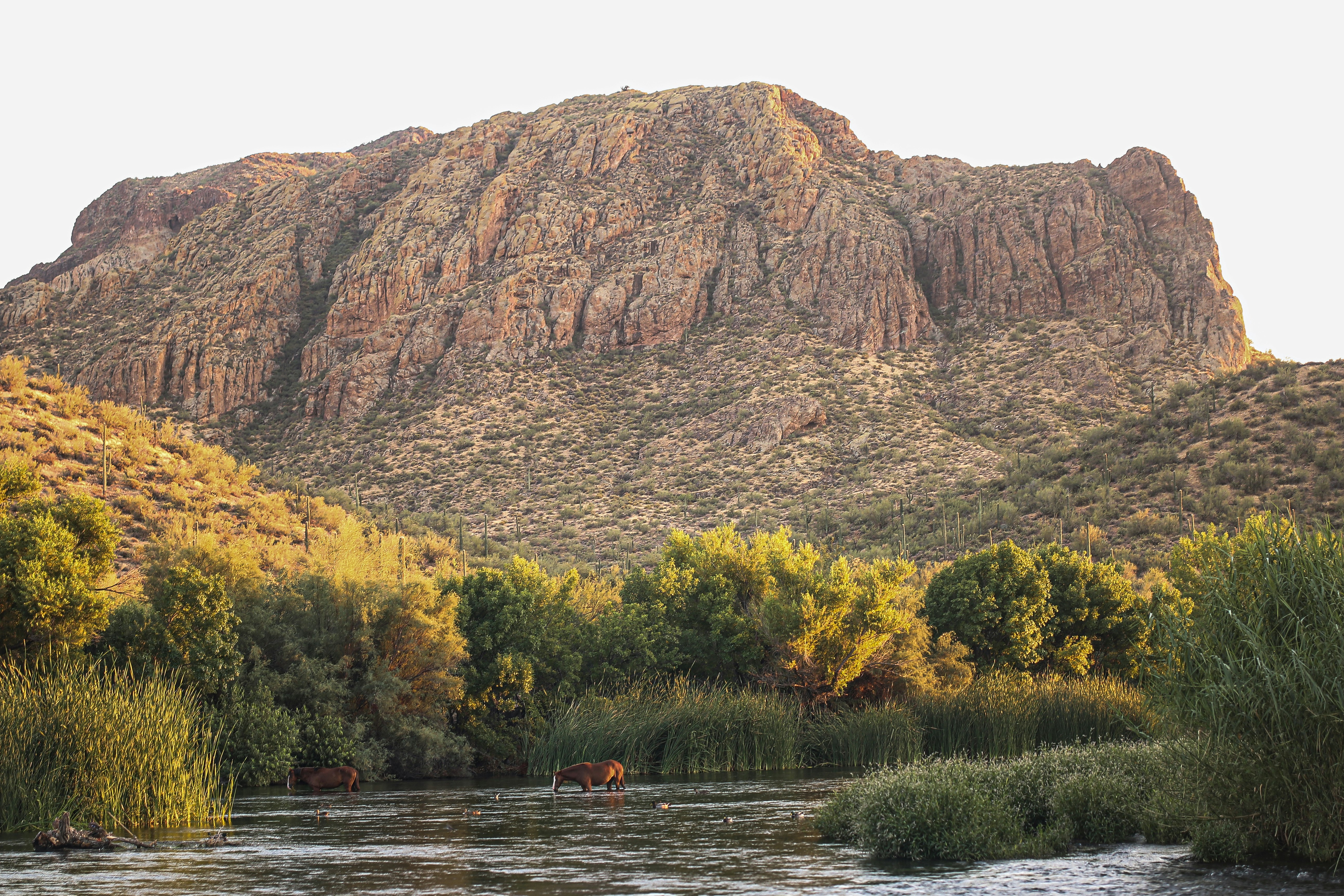 person riding on boat on river near brown mountain during daytime