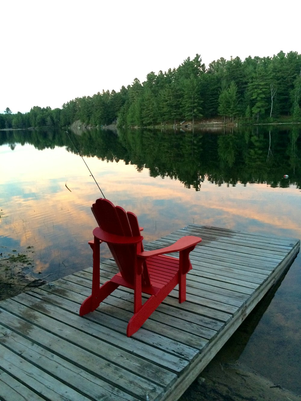 poltrona de madeira vermelha na doca perto do lago durante o dia