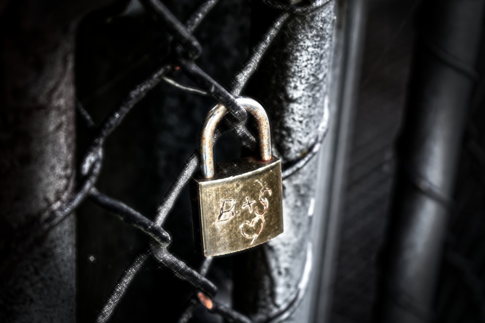 brass padlock on black metal fence