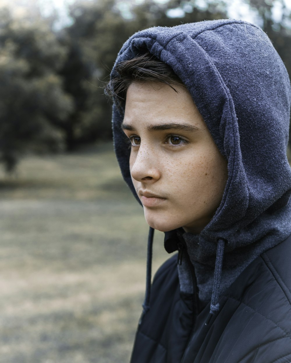 boy in blue hoodie standing on field during daytime