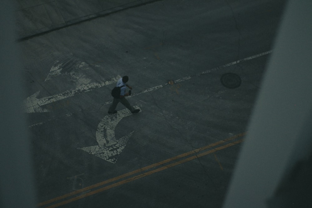 man in blue shirt and black pants walking on black asphalt road