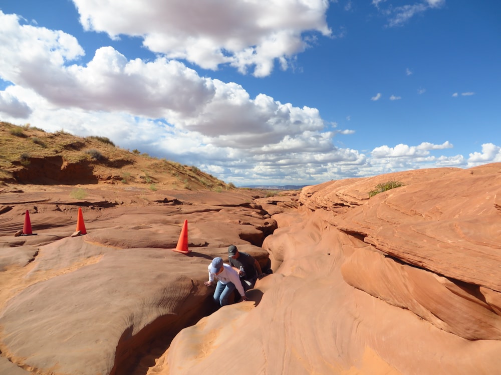 woman in blue jacket sitting on brown rock formation under blue sky during daytime