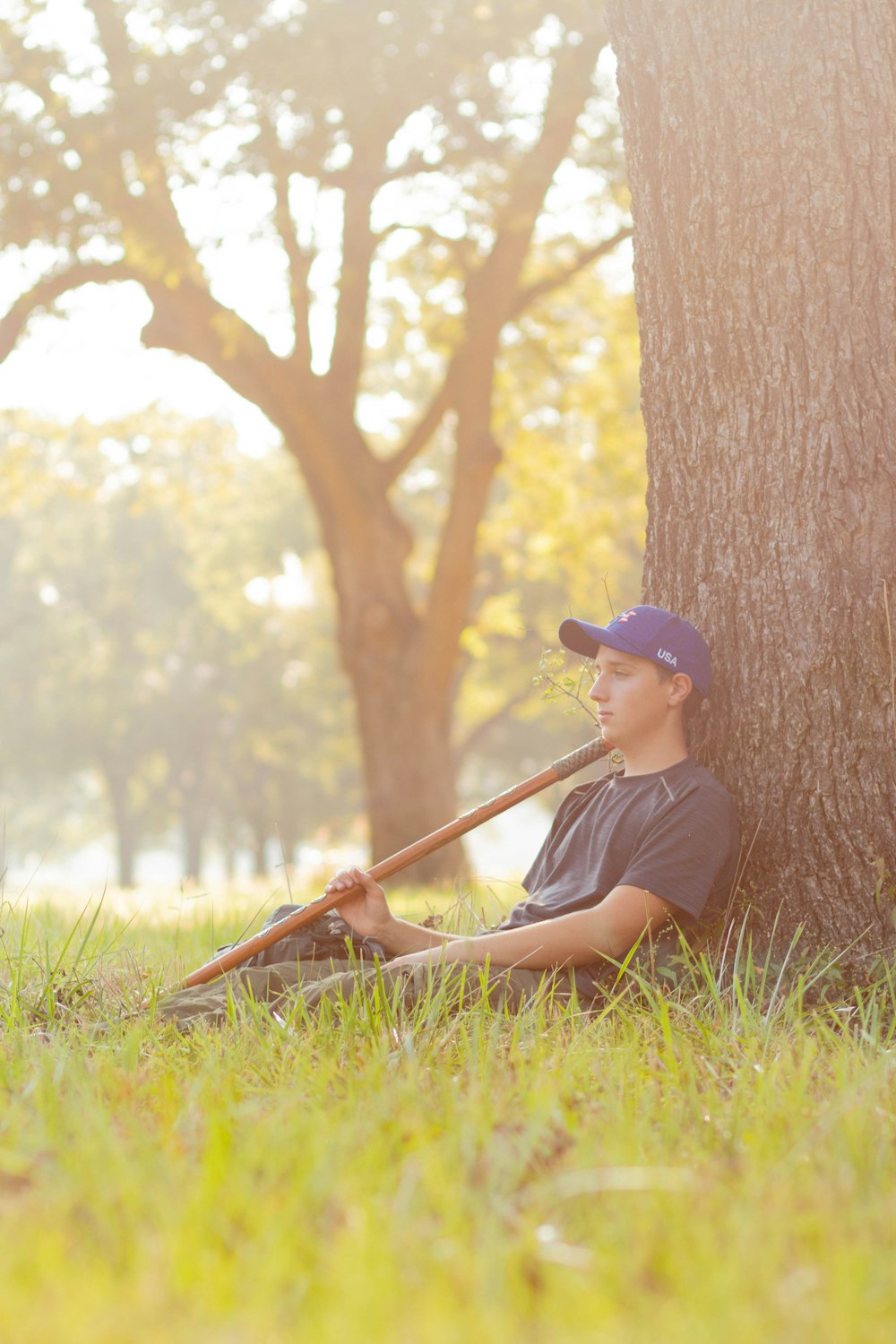 man in black shirt sitting on green grass field during daytime