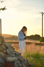 A close-up of a farmer using a smartphone app in a lush green field during golden hour.