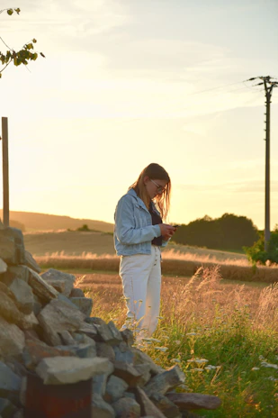 A close-up of a farmer using a smartphone app in a lush green field during golden hour.