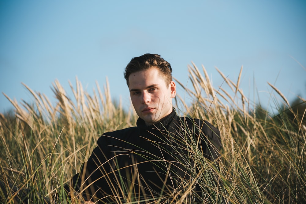 man in black crew neck shirt standing on green grass field during daytime