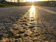 Sunset view of a sealed asphalt road reflecting warm light, emphasizing durability and care.