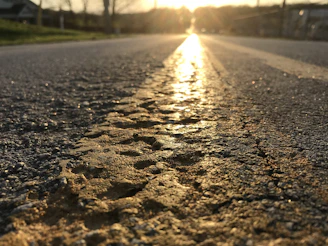 Close-up of fresh asphalt being laid on a city street at sunrise.